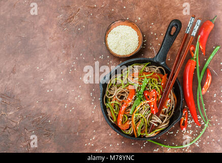 Buchweizen Soba Nudeln mit Karotten, Paprika, Zucchini, Frühlingszwiebeln und Sesam - ein traditionelles Gericht der asiatischen Küche. Vegetarisches Gericht. Selektive Stockfoto