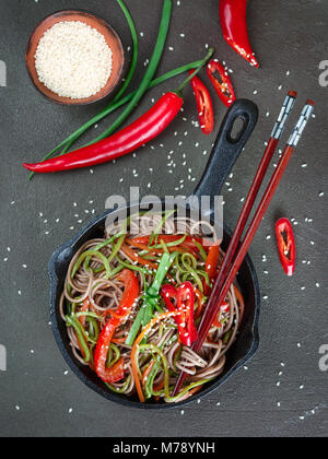 Buchweizen Soba Nudeln mit Karotten, Paprika, Zucchini, Frühlingszwiebeln und Sesam - ein traditionelles Gericht der asiatischen Küche. Vegetarisches Gericht. Selektive Stockfoto