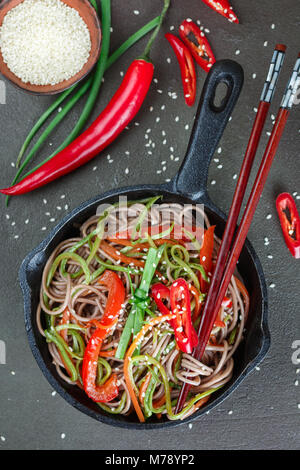 Buchweizen Soba Nudeln mit Karotten, Paprika, Zucchini, Frühlingszwiebeln und Sesam - ein traditionelles Gericht der asiatischen Küche. Vegetarisches Gericht. Selektive Stockfoto