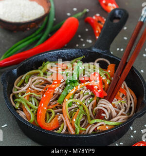 Buchweizen Soba Nudeln mit Karotten, Paprika, Zucchini, Frühlingszwiebeln und Sesam - ein traditionelles Gericht der asiatischen Küche. Vegetarisches Gericht. Selektive Stockfoto