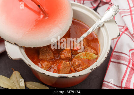 Gulasch ist ein traditionelles ungarisches Gericht von geschmortem Rindfleisch mit Gemüse in einer dicken Tomatensauce mit Gewürzen in einen gusseisernen Topf. Selektiver Fokus Stockfoto