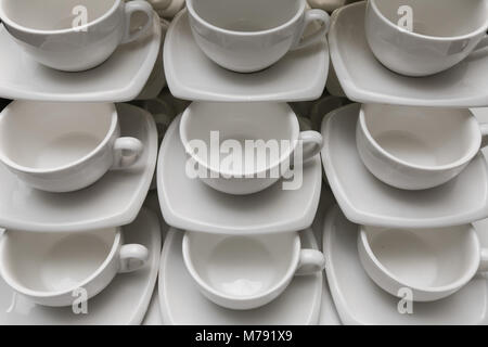 Viele Zeilen saubere weiße Tasse Kaffee, Kaffee Löffel und Untertasse auf Tisch. Leere Becher in der Zeile für Kaffeepause vorbereiten Stockfoto