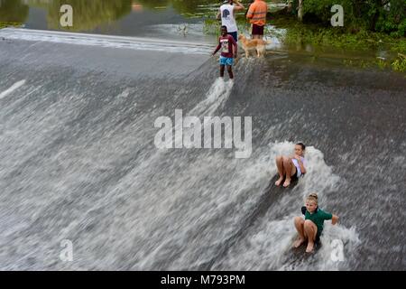 Kinder spielen im fließenden Wasser als Wasser Kaskaden über Aplins Wehr nach Stürmen und Starkregen, Aplins Wehr, Townsville, Queensland, Australien Stockfoto