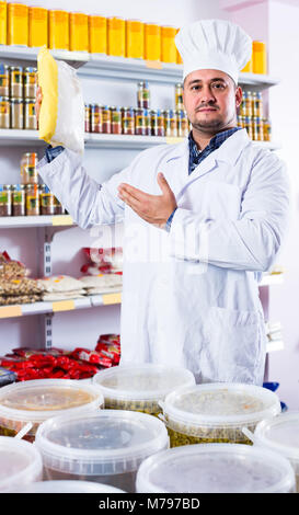 Happy europäischen shop Personal bietet Lebensmittel und gefüllten Regalen hinter Stockfoto
