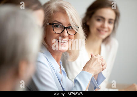 Lächelnd im Alter von Geschäftsfrau, schauen, hören, Kollegen bei Kaffee Stockfoto