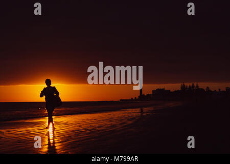 Walker am Strand mit Leuchtturm bei Sonnenuntergang in Maspalomas, Gran Canaria. Stockfoto