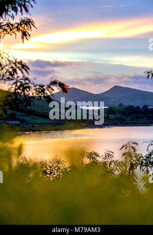 Sonnenuntergang auf tropischen Fidschi Insel mit Blick auf Büsche, den Atlantik und die Berge. Zwei Hügel im Hintergrund. Reflexion der warmen orange Farben auf Ruhe wa Stockfoto