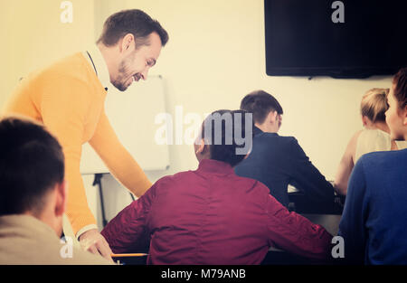 Junge Lehrer, die Erläuterung der Schüler während der Arbeit in der Klasse Revision Stockfoto