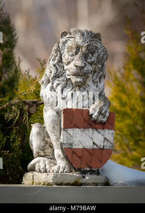 Kleine Figur eines Löwen in einem Garten mit einem roten und weißen Schild Stockfoto