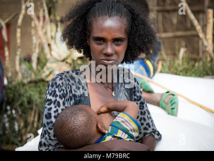 Raya Stamm frau Ihr Baby füttern, mit einem schönen Frisur und lockige Haare, Semien Wollo Zone, Woldia, Äthiopien Stockfoto