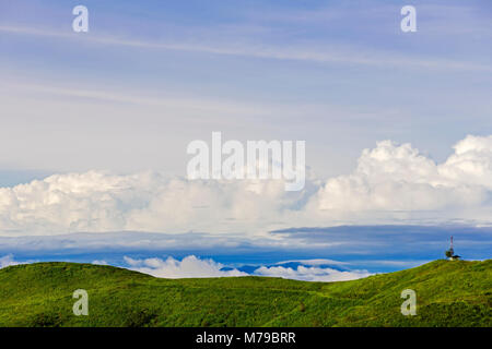 Ein kleines Haus mit einem Funksender auf der Spitze des Hügels mit einer Wolke im Hintergrund. Stockfoto