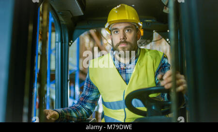 Nahaufnahme eines Gabelstapler Fahrer professionell Betrieb des Fahrzeugs in einem grossen Lager voll von Racks mit Paletten. Stockfoto