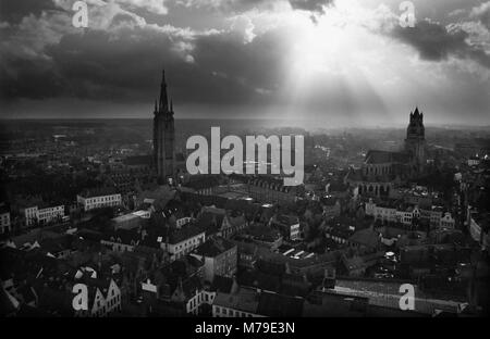 Blick über die Stadt vom Belfort, Brugge, Belgien: Eine dramatische Himmel mit der Sonne durch die Wolken brechen. Schwarz-weiß Film Fotografie, ca. 1985 Stockfoto