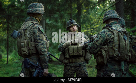 Squad Leader bespricht Militärische Operation Details mit Soldaten, Commander gibt Aufträge. Voll ausgestattete und bewaffneten Soldaten bereit für Mission im Wald Stockfoto