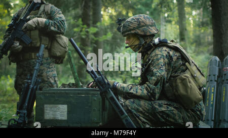 Militärische Inszenierung Base, Chief Army Engineer Sitzen auf den Kisten mit Munition verwendet Armee Grade Laptop Ausgestellt von militärisch-industrielle Komplex. Stockfoto