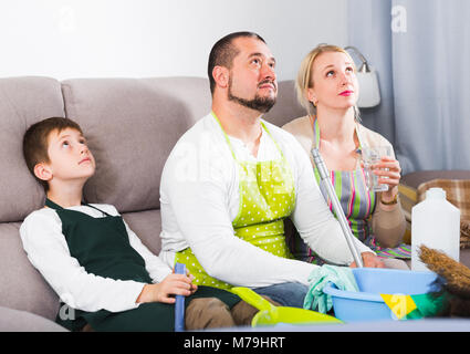 Müde Eltern mit Sohn für die Reinigung auf der Couch zu Hause ruhenden gekleidet Stockfoto