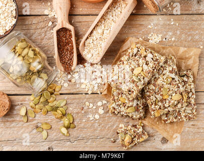 Gesunde Snack - knusprig Cornflakes Cookies auf alten Holztisch und Zutaten: Haferflocken, Leinsamen, Kürbis-, Sonnenblumen-, Sesam. Diät crispy Cracker. Se Stockfoto