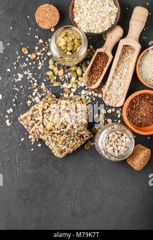 Gesunde Snack - knusprig Cornflakes Cookies auf schwarzen Steintisch und Zutaten: Haferflocken, Leinsamen, Kürbis-, Sonnenblumen-, Sesam. Diät crispy Cracker. c Stockfoto