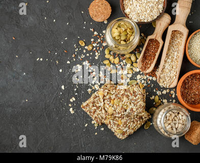 Gesunde Snack - knusprig Cornflakes Cookies auf schwarzen Steintisch und Zutaten: Haferflocken, Leinsamen, Kürbis-, Sonnenblumen-, Sesam. Diät crispy Cracker. c Stockfoto