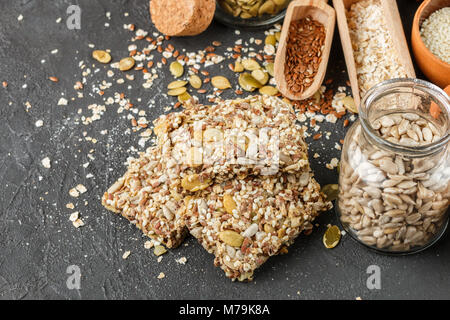 Gesunde Snack - knusprig Cornflakes Cookies auf schwarzen Steintisch und Zutaten: Haferflocken, Leinsamen, Kürbis-, Sonnenblumen-, Sesam. Diät crispy Cracker. S Stockfoto