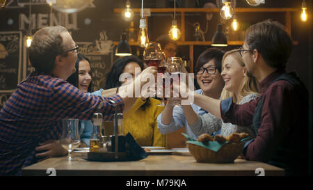 Vielfältige Gruppe von Freunde Feiern mit einem Toast und Clink angehoben Weingläser in der Feier. Schöne junge Leute haben Spaß in der stilvollen Bar Stockfoto