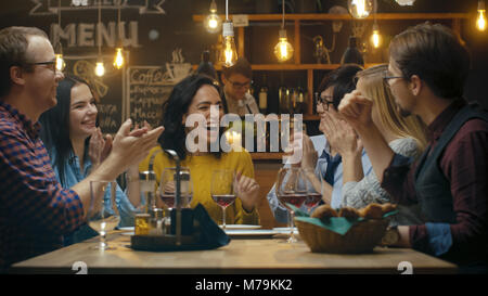 In der Bar/Restaurant Schöne Hispanic Frau Aktien gute Nachrichten mit Ihrer Liebe Freunde Sie gratulieren ihr herzlich und applaudieren. Stockfoto