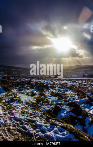 Sonnenstrahlen durch die Wolken an einem verschneiten Tag, Burbage, Peak District Stockfoto