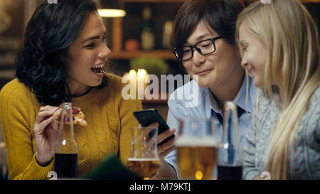 Vielfältige Gruppe von jungen Leuten viel Spaß in der Bar, Reden, erzählen Geschichten und Witze. Sie trinken, verschiedene Getränke. Sie sind in der stilvollen Hipster Bar Stockfoto