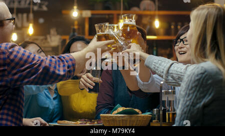 Vielfältige Gruppe von Freunden einen Toast und Clink angehoben Gläser mit verschiedenen Getränken in der Feier. Schöne junge Leute haben Spaß in der stilvollen Bar Stockfoto