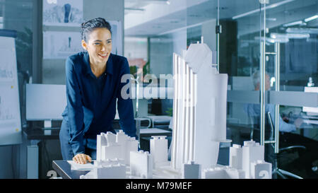 Long Shot der weiblichen Architektur Designer das Hinzufügen von Komponenten zu einem Gebäude, Modell, Sie arbeitet auf einem Stadtteil Stadtplanung Projekt. Stockfoto