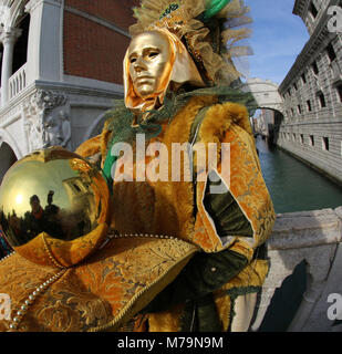 Venedig, Italien - Februar 5, 2018: der Mann, der mit Gold Glove in der Hand und ein goldenes Kleid mit Maske in der Nähe der berühmten Seufzerbrücke genannt Ponte dei Sospiri in Stockfoto