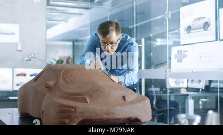 Erfahrung Automotive Designer mit einer Harke formt Prototyp Auto Modell aus Plastilin Ton. Er arbeitet in einem modernen Studio in einem großen Automobilkonzern Stockfoto