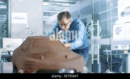 Erfahrung Automotive Designer mit einer Harke formt Prototyp Auto Modell aus Plastilin Ton. Er arbeitet in einem modernen Studio in einem großen Automobilkonzern Stockfoto