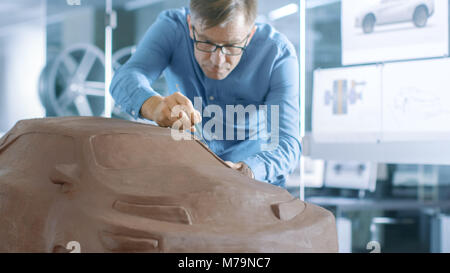 Erfahrung Automotive Designer mit einer Harke formt Prototyp Auto Modell aus Plastilin Ton. Er arbeitet in einem modernen Studio in einem großen Automobilkonzern Stockfoto