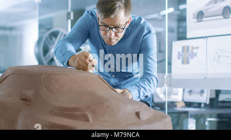 Erfahrung Automotive Designer mit einer Harke formt Prototyp Auto Modell aus Plastilin Ton. Er arbeitet in einem modernen Studio in einem großen Automobilkonzern Stockfoto