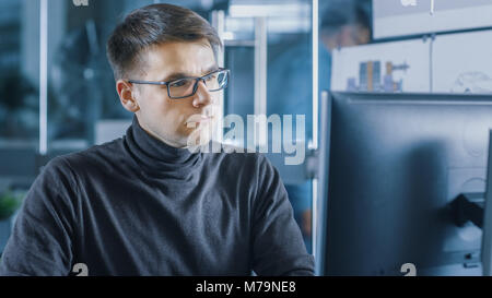 Junge männliche Wirtschaftsingenieur arbeitet auf einem Personal Computer. Stattliche intelligenter Mann in dem hellen, modernen Büro. Stockfoto