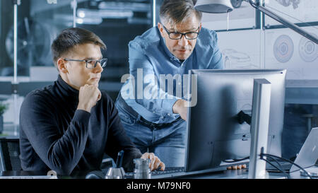 Erfahrene Senior Engineer berät junge Designer über Projekt, Haben Sie die Diskussion und die Arbeit an einem PC. Stockfoto