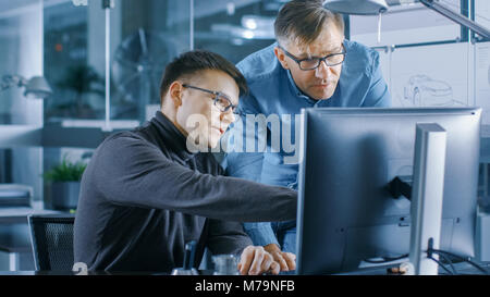 Erfahrene Senior Engineer berät junge Designer über Projekt, Haben Sie die Diskussion und die Arbeit an einem PC. Stockfoto