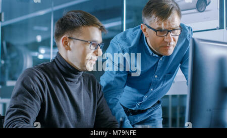 Erfahrene Senior Engineer berät junge Designer über Projekt, Haben Sie die Diskussion und die Arbeit an einem PC. Stockfoto