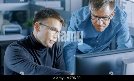 Erfahrene Senior Engineer berät junge Designer über Projekt, Haben Sie die Diskussion und die Arbeit an einem PC. Stockfoto