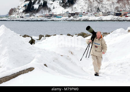 Fotograf mit einem großen Objektiv (600 mm) im Schnee Stockfoto
