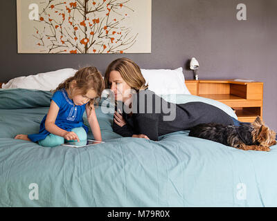 Eine Frau, die ihre Tochter Beobachten lernen, wie man mit einem ipad mini schreiben. Stockfoto