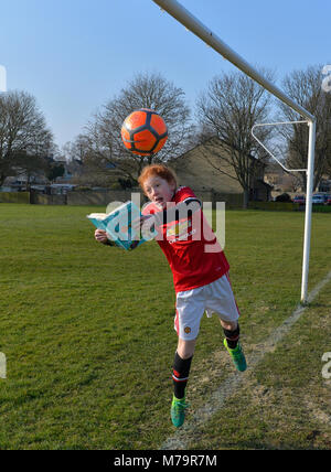 Mädchen spielt Fußball und liest Stockfoto