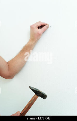 Die Hand des Mannes ist, einen Nagel in die Wand ein Bild zu hängen. Stockfoto