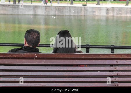 Ein paar sitzen auf einer Bank mit Blick auf das Wasser Stockfoto
