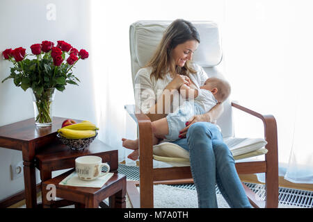 Mutter, spielt mit ihren Toddler boy zu Hause im Schaukelstuhl, lächelnd, stillen Stockfoto