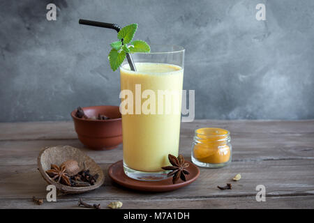 Gelbwurz Lassie oder Lassi aus Glas - gesunden probiotischen Indischen kaltes Getränk aus Quark (Joghurt), Milch, Gewürzen und Zucker. Gelbwurz Smoothie auf Holz, Stockfoto