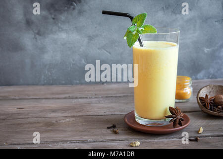 Gelbwurz Lassie oder Lassi aus Glas - gesunden probiotischen Indischen kaltes Getränk aus Quark (Joghurt), Milch, Gewürzen und Zucker. Gelbwurz Smoothie auf Holz, Stockfoto