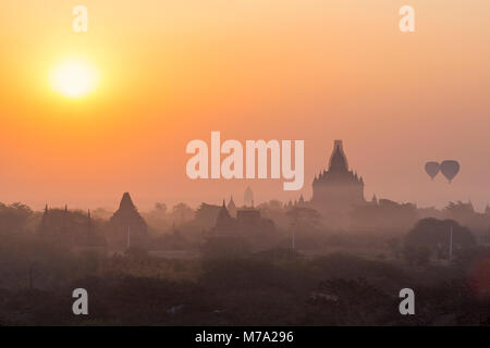 Sonnenaufgang und Heißluftballons über Tempeln in Backstein Damm in der Nähe von Taungbi Dorf in Bagan, Myanmar (Birma), Asien im Februar Stockfoto