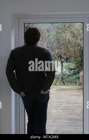 Mann in Türdurchgang in seinem Garten und Vogelbeobachtung Stockfoto